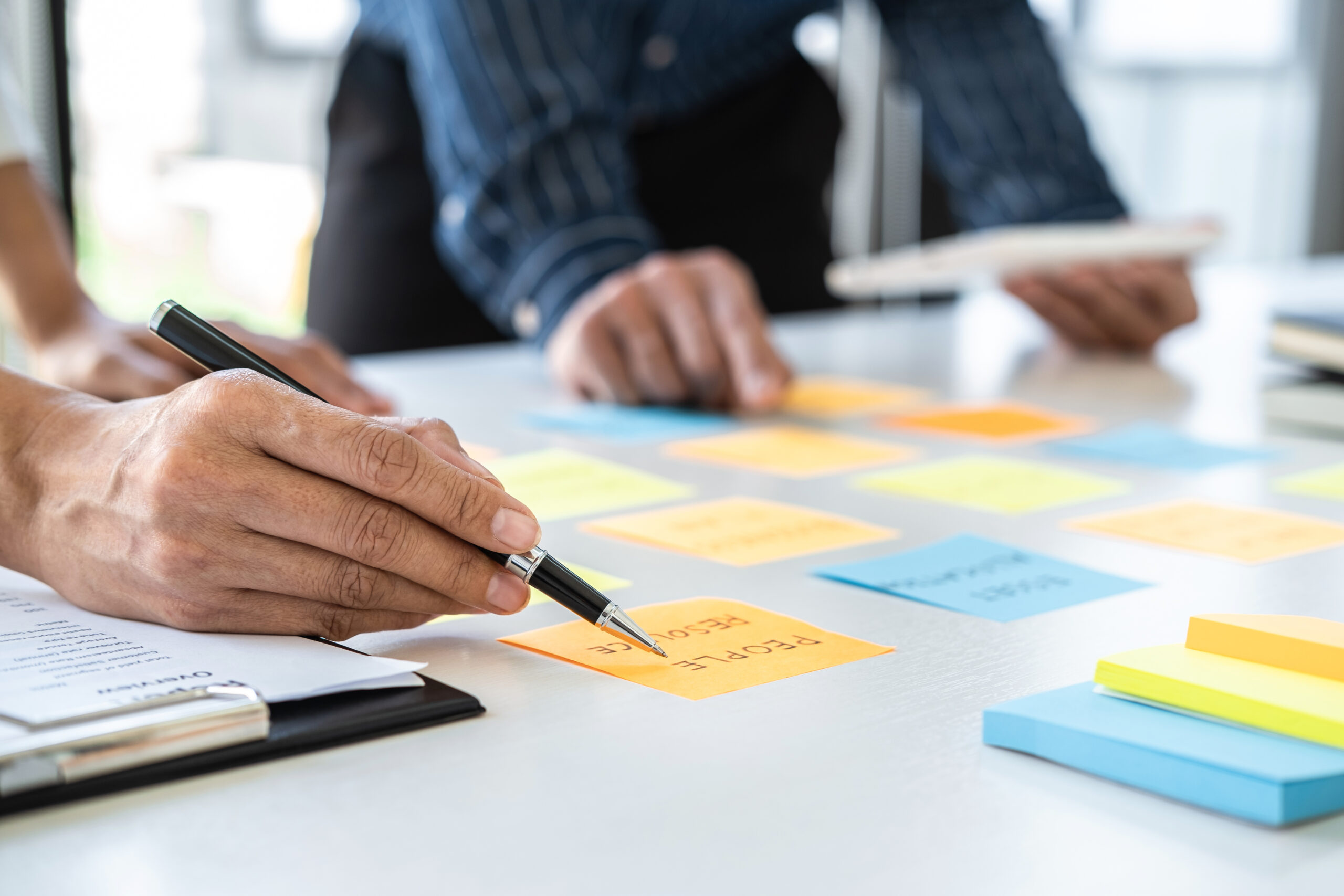 Two creative business people meeting and planning use post it notes sticky note on desk to share idea, Analysis data chart and graph with teamwork strategy brainstorming in office.
